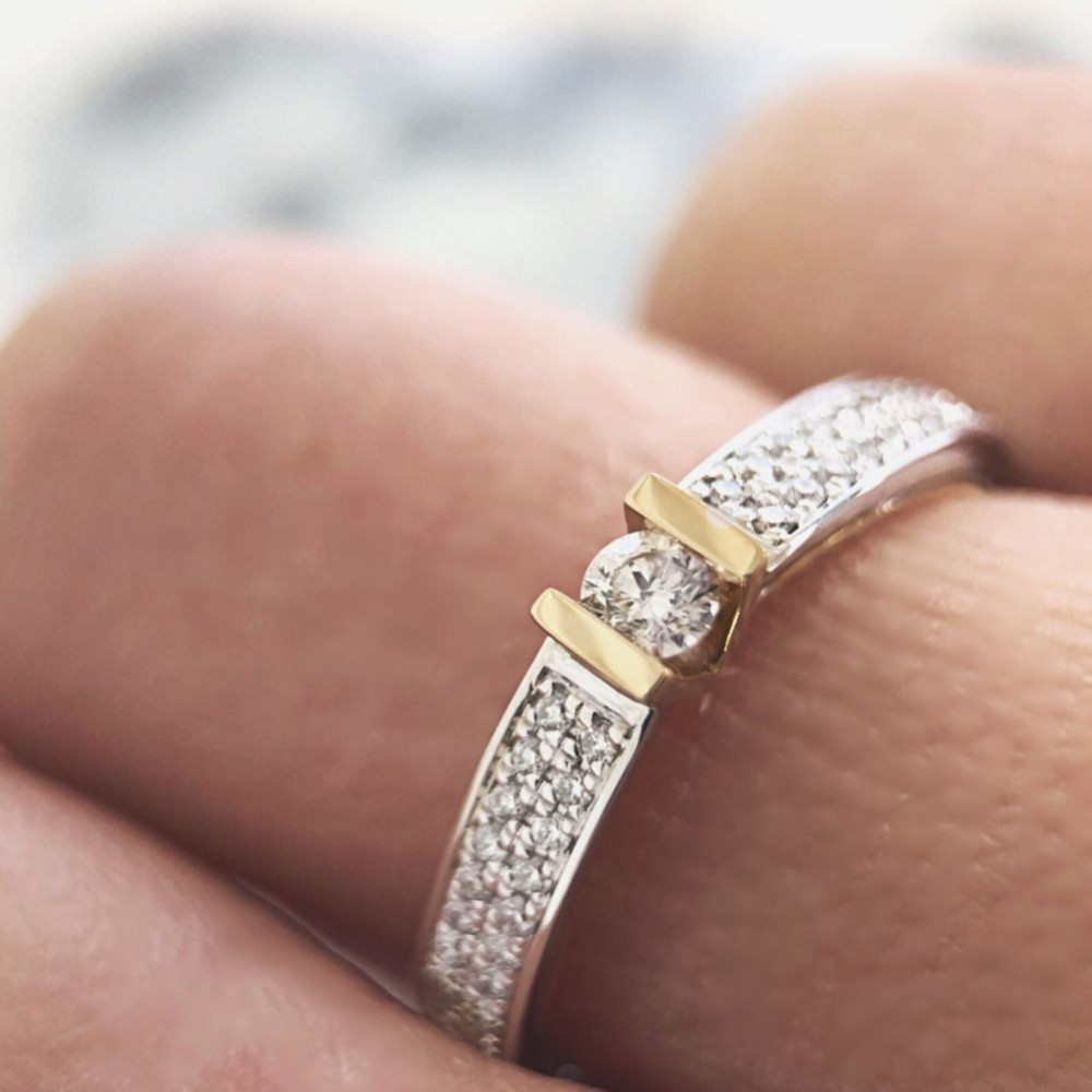 solitair-ring-van-14-karaat-witgoud-met-geelgoud-met-centrale-diamant-en-pave-gezette-zijstenen